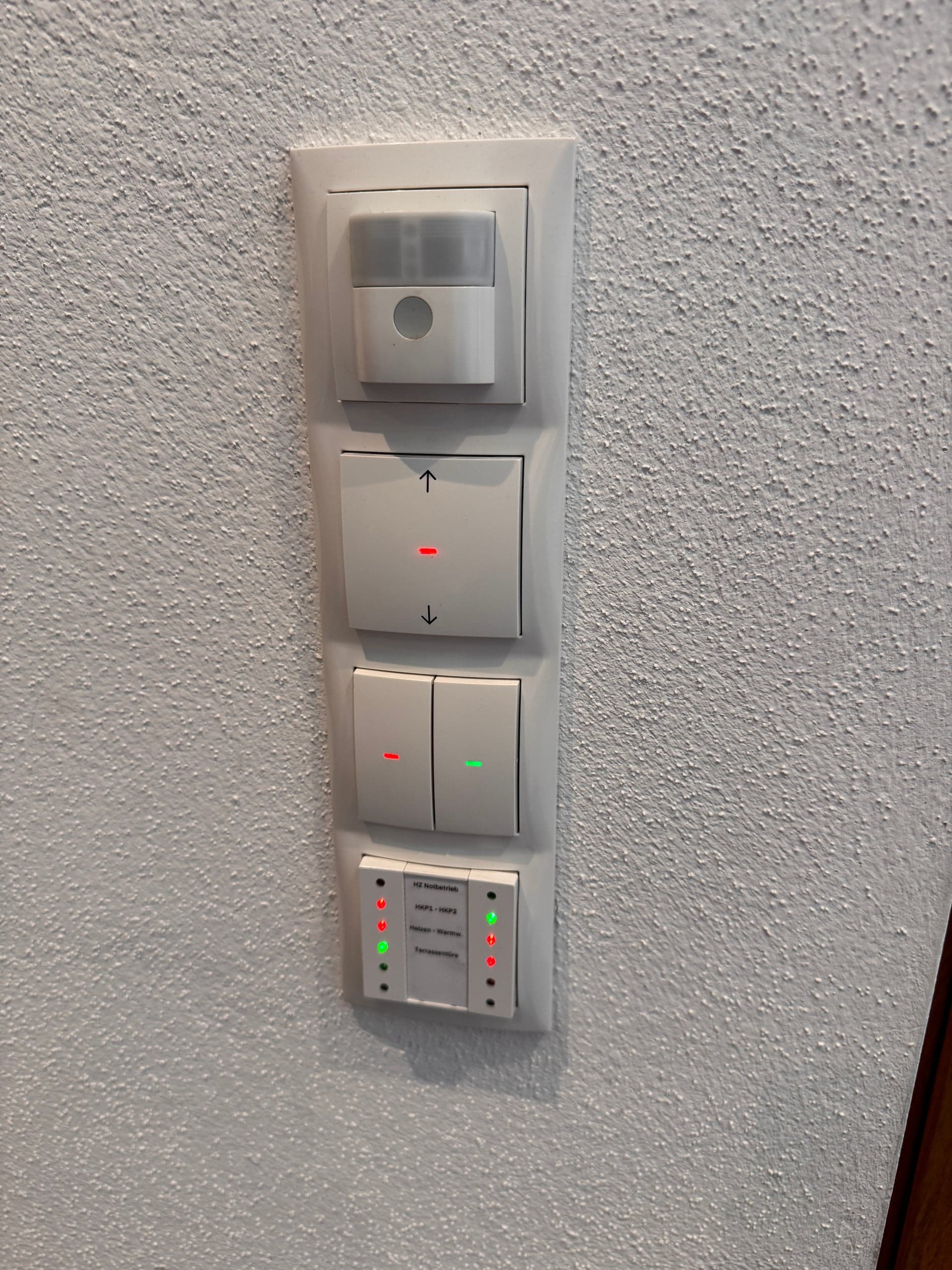 KNX-Touchpanel an einer Haustüre zeigt den aktuellen Smart-Home-Status mit Symbolen für Fenster, Beleuchtung und Sicherheitssystem
